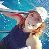 杰斯·菲尼克斯(Jess Phoenix)戴着一顶棒球帽，在清澈的蓝色海水中的一艘船上